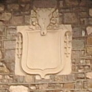 a garlanded cow skull carved of stone is positioned above a carved stone shield
