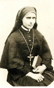 Photo d'une jeune religieuse assise, une croix sur la poitrine, un livre sur les genoux