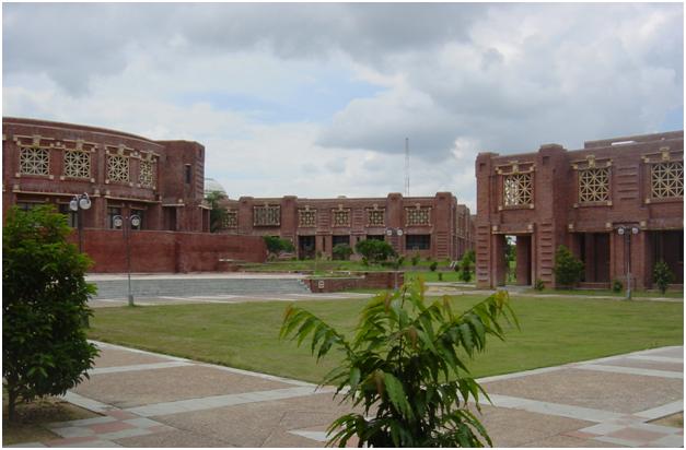 Grassy quadrangle in front of low, red buildings