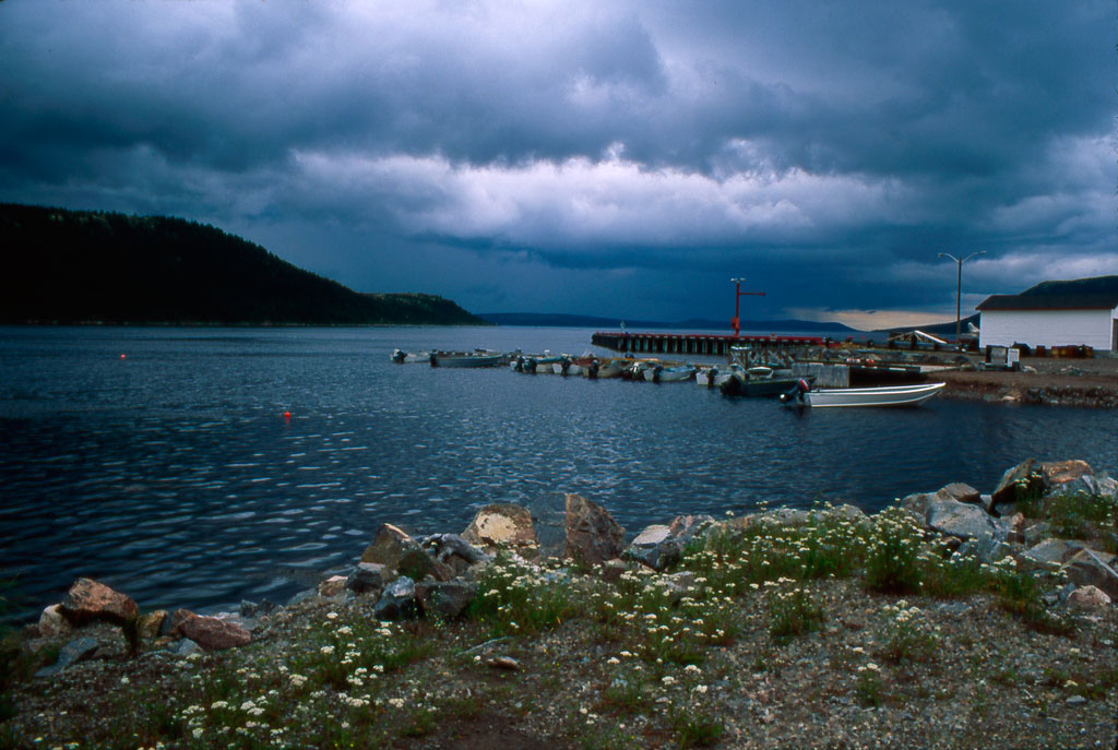A harbour in Rigolet at dusk showing the dark blue ocean and the very overcast sky