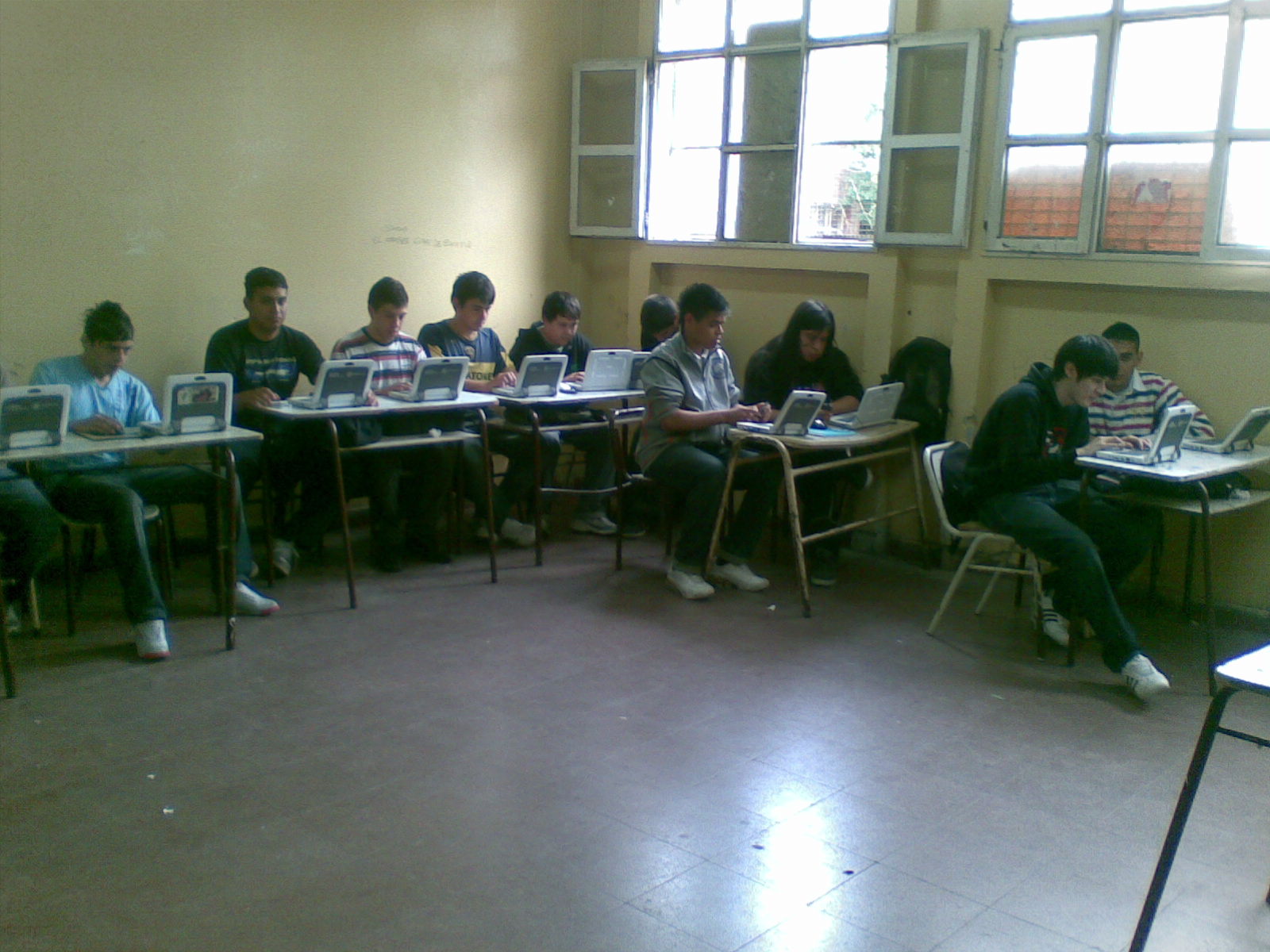 Alumnos de una escuela tecnica trabajando con computadoras. Se observa una disposición tradicional del espacio aulico.
