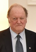 Head and shoulders of Bill Sheat smiling and dressed in a dark suit