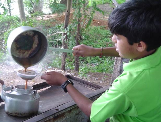 A boy preparing tea at a typical tea stall in India