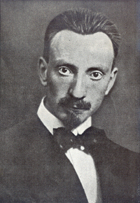 Portrait noir et blanc d'un homme coiffé cheveux plaqués en arrière, regard fixe, nez prédominent, portant moustache, veste, chemise blanche et nœud papillon au cou.