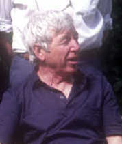 a white-haired late-middle aged man in a dark blue casual shirt