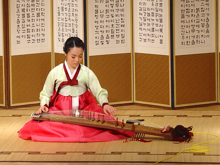 A musician playing a 12-string sanjo gayageum