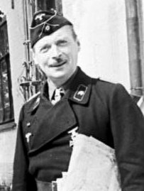 A smiling man in a black uniform holding a sheaf of documents