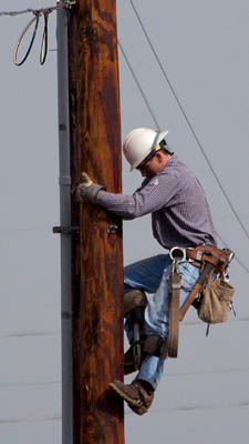 Cropped version:A worker climbing down an elec...
