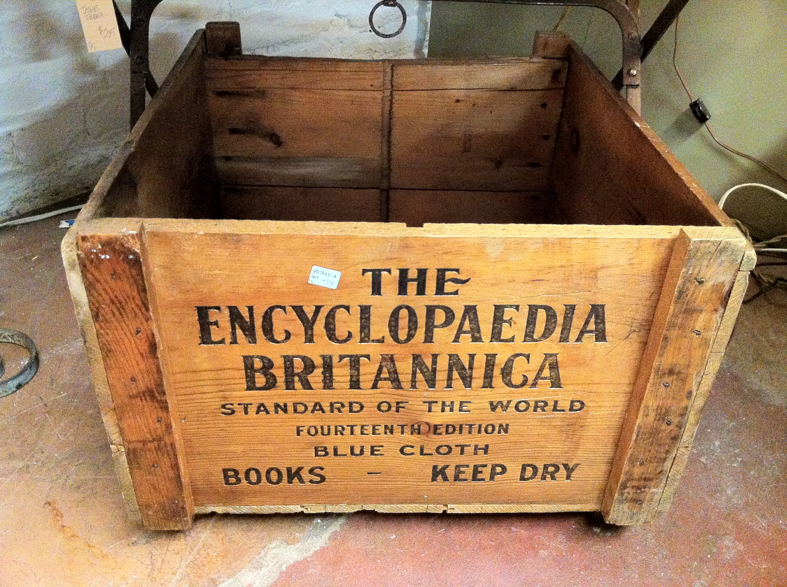 A wooden crate reading "THE / ENCYCLOPAEDIA / BRITANNICA / STANDARD OF THE WORLD /