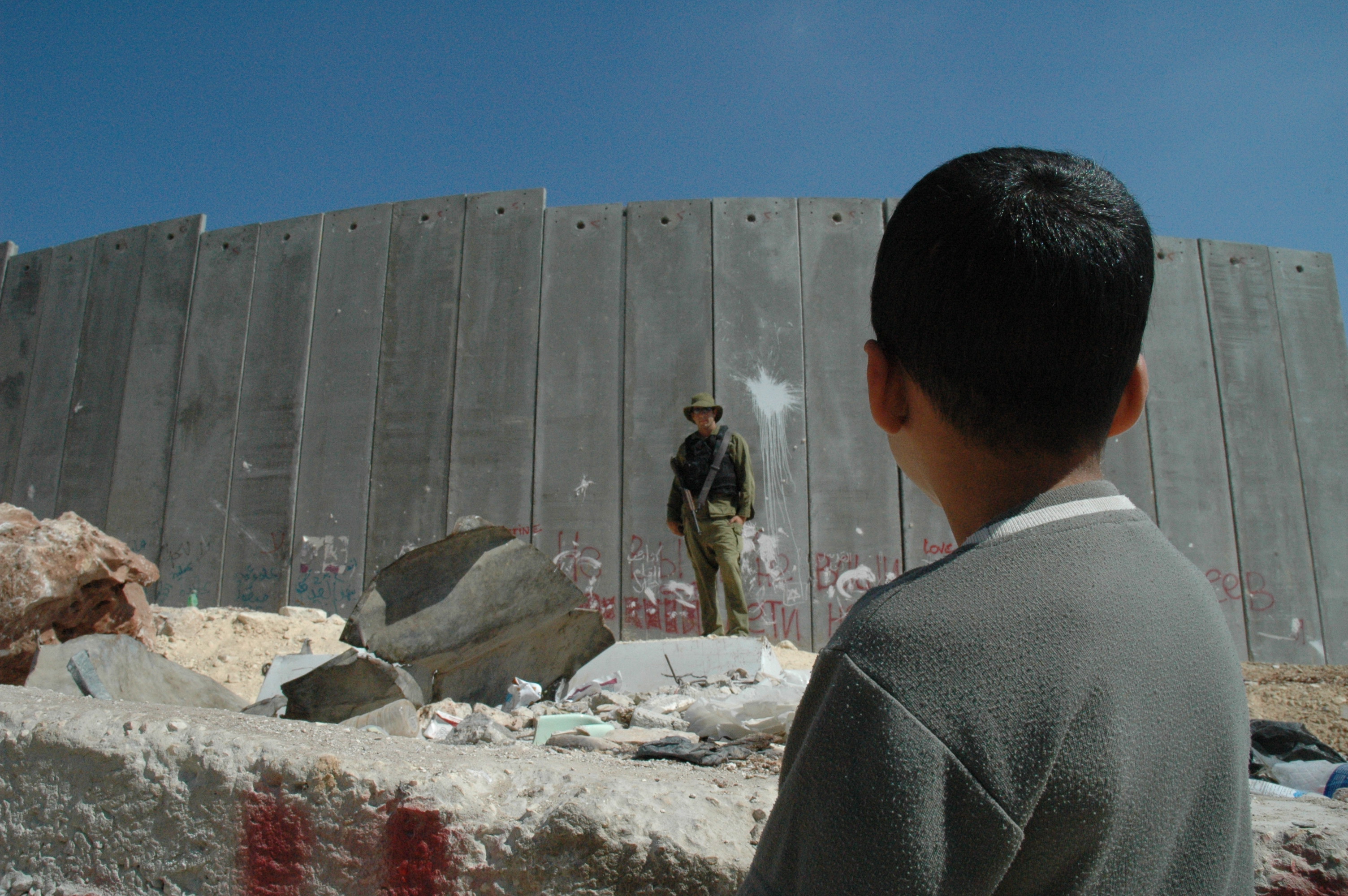 A boy and soldier in front of the West Bank Barrier