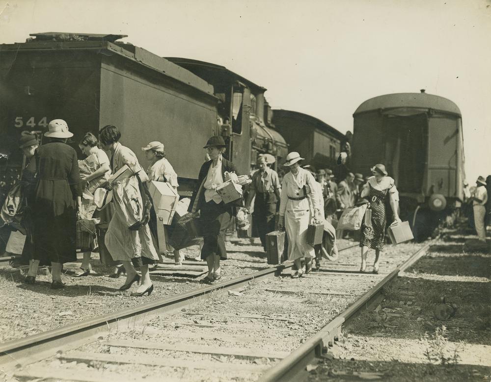 StateLibQld_1_251348_Women_loaded_with_parcels_and_cases,_leaving_a_train_via_the_tracks.jpg