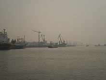 port quayside can be seen shrouded in hazy fog, obscuring cranes and piers