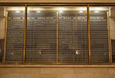 A large blackboard for train schedules, hanging behind glass