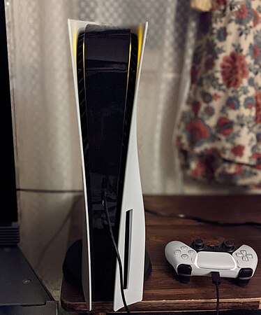 The PlayStation 5 Blu-Ray model with DualSense controller at the base of the unit.