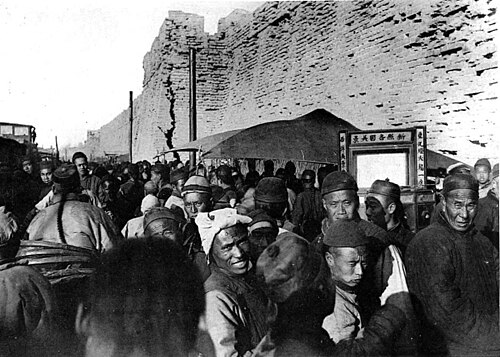 Foule autour d’un théâtre ambulant le long de la muraille de Tien-Tsin. - Le rideau, heureusement baissé, cache aux yeux des Européens les sujets, plutôt légers, dont le Chinois fait ses délices