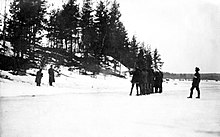Расстрел белых расстреливает двух красных солдат из винтовок в зимнем поле у ​​небольшого холма. За расстрельной командой стоит лидер отряда белых.