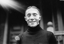 Photographie en noir et blanc d'un jeune homme souriant vu en contre-plongée.