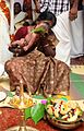 Image 17A new born's Namakarana ceremony. The grandmother is whispering the name into the baby's ear, while friends and family watch. (from Samskara (rite of passage))