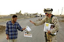 U.S. Army soldier hands out a newspaper to a local in Mosul, Iraq. US Army soldier hands out a newspaper to a local Aug 2004.jpg