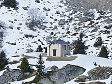 Photo de la chapelle Notre-Dame-des-Anges d'Orelle, avec sa porte et ses façades sous la neige.