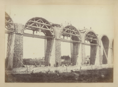 Photographie en sépia montrant les structures en arc de cercle supportant les arches durant leur construction, trois cintres sont montés simultanément.