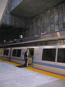 Una plataforma casi vacía de una estación de tren, con una persona a punto de entrar en un tren