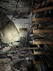 A room with broken oars and large pieces of concrete on the ground from the collapsed ceiling