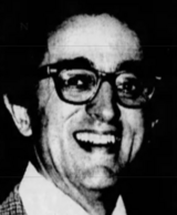 A grainy, black-and-white photo of a young white man looking at the camera with a smile.