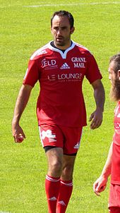 Un joueur de rugby vêtu de rouge, de face, marchant.