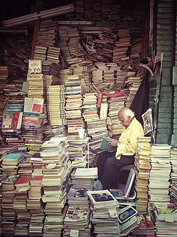 Man reading among a large pile of books
