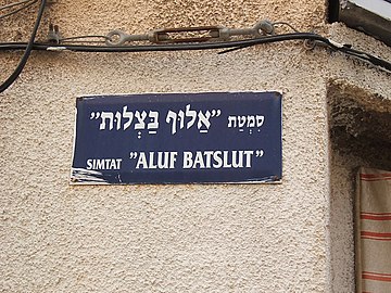 Hebrew street sign, above in Hebrew alphabet, below in Latin transliteration. Aluf Batslut veAluf Shum(he) ("The Knight of Onions and the Knight of Garlic") is a story by Hayim Nahman Bialik.