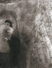 Photo en noir et blanc d'un homme à tonsure, de dos, dans un tunnel.