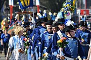 Zünfter der Zunft zu den Drei Königen mit Wappenbildern auf der Brust, begleitet von einem Blumenmädchen