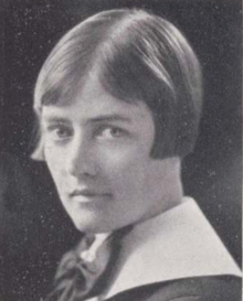 A young white woman with hair cropped to the cheekbone; wearing a stiff white collar and a large dark bow