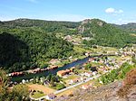 Foto einer an einem Fluss gelegenen Ortschaft in hügliger Umgebung