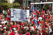 Thousands of Gibraltarians dress in their national colours of red and white during the 2013 Gibraltar National Day celebrations. Gibraltarians were the only group of overseas territories residents who could apply for full British citizenship without restrictions before 2002. Gibraltar National Day 011 (9719769048) (3).jpg