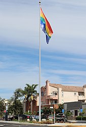 A rainbow flag on a tall flagpole