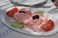 Taramasalata guarnecida de azeitonas, pepino e tomate.