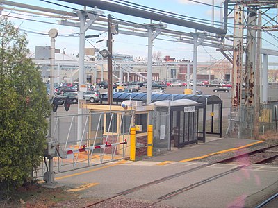 A railway platform and small shelter, with industrial facilities visible behind