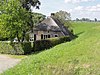 Boerderij, gedateerd op een geschilderde zonnewijzer. Rieten wolfdak; voorgevel met vlechtingen en vensters met zesruitsschuiframen, waarvoor luiken