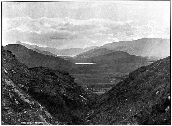 Looking down a mountain valley with a lake in the middle distance and more mountains behind.