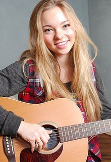 A blond woman holding a guitar