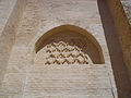 Niche en arc brisé, à fond plat orné d’un décor géométrique losangé. L’arc est le vestige d’une ancienne entrée murée.