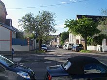 Photo récente d'un rue en pente, avec des maisons et quelques arbres