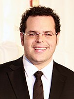 A black-haired, bespectacled Josh Gad