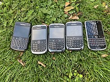 5 mobile phones that have been shown on grass and are being sold at a car boot sale.