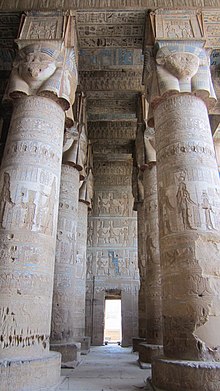 Room with tall stone columns topped by faces of women. The columns, walls, and ceiling are covered in painted reliefs.