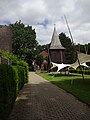 Houten 18e-eeuwse klokkentoren met op de achtergrond het rond 1840 herbouwde kerkje van Jesteburg