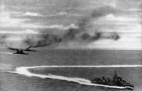 Bitevní loď Prince of Wales (vlevo) a bitevní křižník Repulse (vlevo vzadu) po prvním útoku japonských letadel. V popředí manévrující torpédoborec. Pohled z japonského letounu