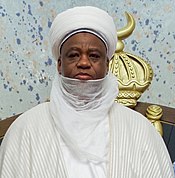 A color photograph of Sa'adu Abubakar, shown from the chest up, wearing white clothing